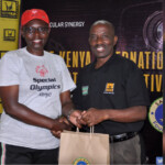 Panelist, Madam Jacqueline Tabbya receives a KISFF, 6TH EDITION-2023, " GOODIE BAG" Courtesy of Safinaz Foundation from Personal Assistant to The Chairman and Festival Director, Pastor John Muli.