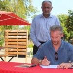 French Ambassador HE Arnaud Suquet signs the visitors book at Alliance Francaise Mombasa during the KISFF 2024 as KISFF chairman Aasif Karim looks on.